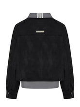 Black cropped jacket with a gray collar featuring three white stripes, a small rectangular metal plaque on the chest, and a gray inner hem, shown from the back on a light gray background.