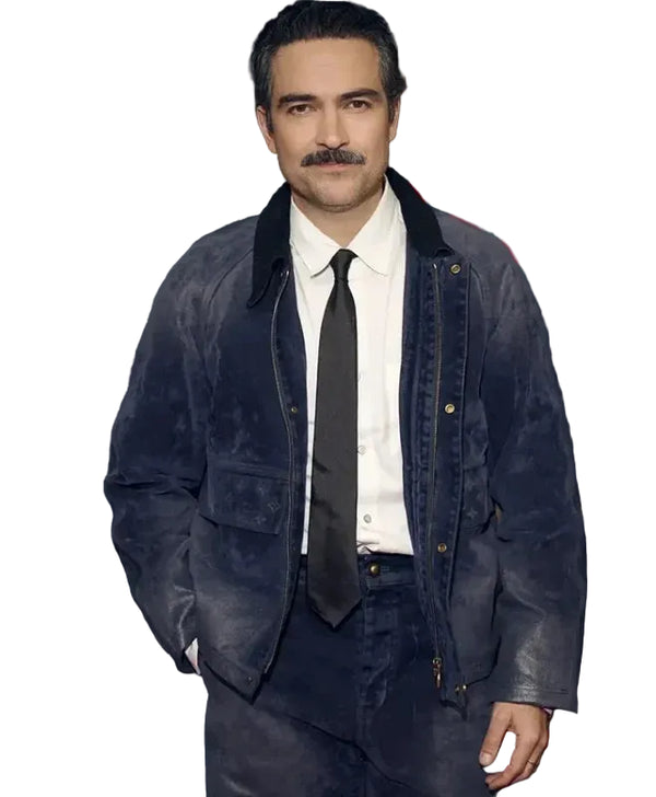 A man with a mustache wearing a dark blue distressed suede jacket, white dress shirt, and black tie, standing in front of a dark background with red Netflix logos.