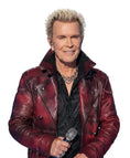 A man with platinum blonde hair wearing a distressed red leather jacket over a black shirt, holding a microphone on a stage with a blue and white lit background.