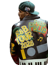 A man shown from behind wearing a black leather jacket with elaborate 'R&B Belle Tour 2026' lettering and guitar graphic details on the back, along with a green baseball cap.