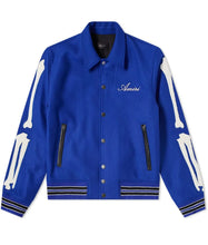 Blue jacket with white bone designs on sleeves and 'Amiri' branding on a white background