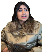 A woman wearing a shiny taupe-brown puffer jacket with a large brown faux-fur collar, shown against a plain white background.