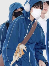 Person wearing a blue raincoat with a hood, carrying a brown bag with a decorative item.