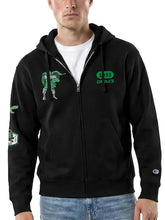 A man wearing a black zip-up hoodie with green and white graphics, featuring a green graphic on the left chest and '1983 en ces' on the right chest, with a Champion logo on the left sleeve cuff.
