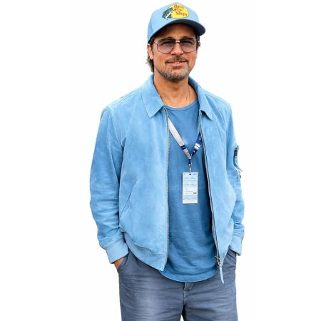 A man wearing a light blue suede jacket, a blue t-shirt, blue jeans, a blue cap, and glasses, standing against a plain white background.