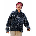 A man wearing a dark navy and gray patterned quarter-zip fleece jacket, a pink headband, and beige pants, isolated on a white background.