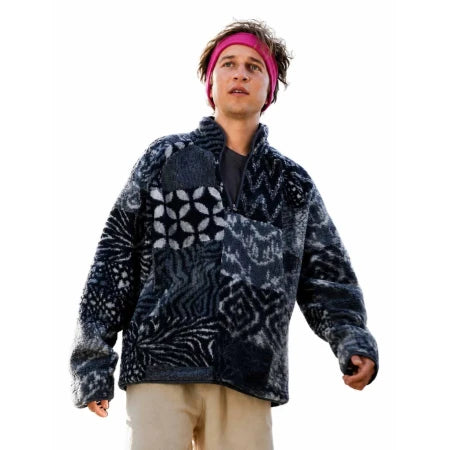 A man wearing a dark navy and gray patterned quarter-zip fleece jacket, a pink headband, and beige pants, isolated on a white background.