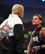 Two men facing each other in a wrestling ring. The man on the left wears a black and white jacket with a large red, white, and black star logo on the back featuring a skull and the text 'Ruthless'.
