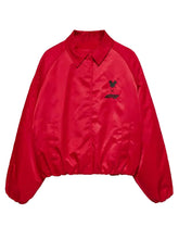 A red nylon coach jacket with a collar, long sleeves, and a small black embroidered logo on the left chest, displayed against a light gray background.