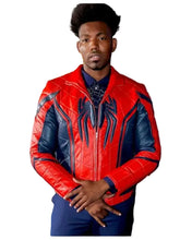 A man wearing a red and navy blue Spider-Man themed leather jacket stands on a blue carpet in front of a dark event backdrop featuring Marvel and Spider-Man branding.