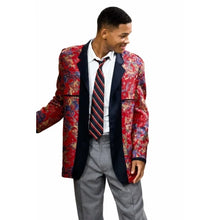 A man wearing a red and blue patterned blazer with dark navy lapels, a white dress shirt, a red and navy striped tie, and gray trousers, shown against a plain white background.