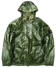 A metallic olive green hooded jacket with a crinkled, reflective finish, featuring a front zipper, zippered chest pockets, and the Stone Island compass patch on the left arm.
