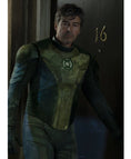 A man wearing a distressed green and black superhero costume with a glowing green emblem on the chest, standing in a dimly lit doorway next to a dark door marked with the number 16.