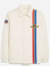 An off-white Coach jacket featuring a vertical red and blue checkered stripe down the front, a gold winged patch, and a small embroidered patch on the sleeve.