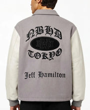 Back view of a gray and off-white varsity-style jacket with a large black gothic 'Nihasha Tokyo' logo and 'Jeff Hamilton' text on the back, worn by a model.