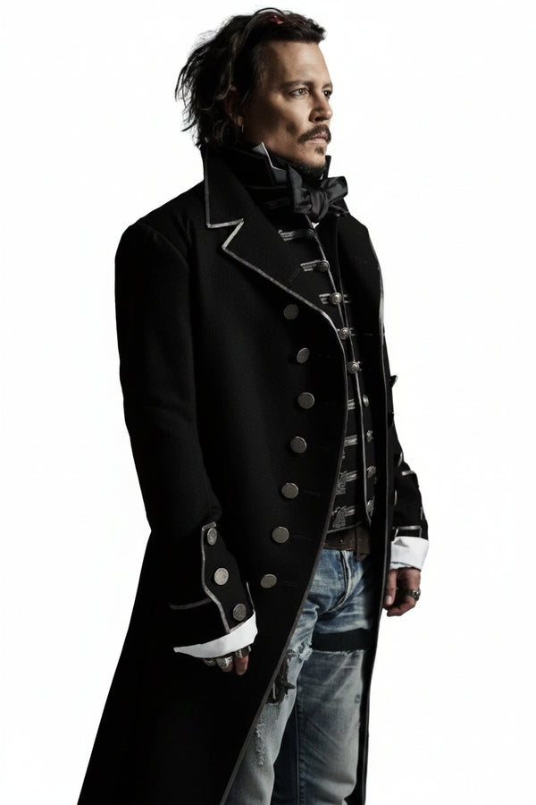 A man wearing a long black military-style coat with silver buttons and trim, layered over a dark vest and light blue jeans, set against a plain white background.