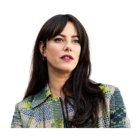 A woman with long dark brown hair and bangs, wearing a green, blue, and beige patterned tweed jacket, shown against a solid white background.