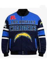 Los Angeles Chargers varsity jacket in blue and navy with a black ribbed collar, cuffs, and hem. Features the team name 'LOS ANGELES CHARGERS' in white and blue, a large yellow lightning bolt logo on the front, and a red 'AA' logo on the upper left chest.