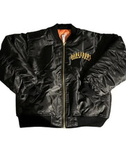 A black satin bomber jacket with a gold zipper, featuring 'DANGEROUS WORLD TOUR' printed in gold on the left chest. The jacket is laid flat against a white background, showing a bright orange lining inside the collar.