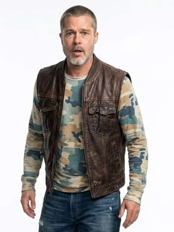 A man wearing a dark brown leather motorcycle vest over a camouflage long-sleeve shirt and blue jeans, standing against a plain white background.