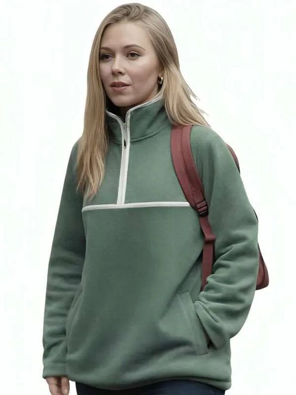 A woman wearing a sage green quarter-zip fleece pullover with a white chest stripe, shown against a plain white background with a dark red backpack strap visible.