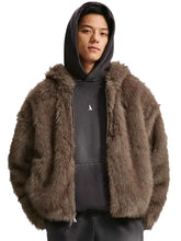 A model wearing a brown faux fur zip-up jacket over a dark gray hoodie and sweatpants, photographed against a solid light gray background.