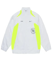 A white zip-up track jacket featuring neon yellow-green side panels and shoulder accents, with a black Palace logo on the right chest, a black Nike swoosh on the left chest, and a circular 'P90' graphic on the front.