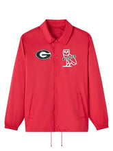A red Coach jacket featuring the Georgia Bulldogs logo on the left chest and the iconic Coach owl logo on the right chest, displayed against a neutral gray background.