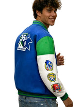 A man wearing a blue, green, and white varsity jacket with Sonic-themed patches on the sleeves and a 35th Anniversary patch on the back, set against a solid gray background.