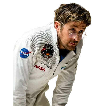 A man wearing a white NASA astronaut training jacket and clear eyeglasses, leaning forward against a solid white background.
