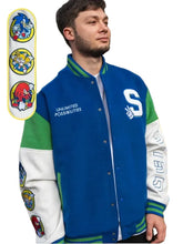 A man wearing a blue, green, and white varsity jacket with Sonic the Hedgehog themed patches and graphics, standing outdoors in front of a graffiti wall.