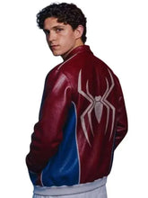 A man wearing a Spider-Man themed leather jacket, shown from the back and side. The jacket is burgundy red with blue panels on the sides and a large white spider emblem on the back.