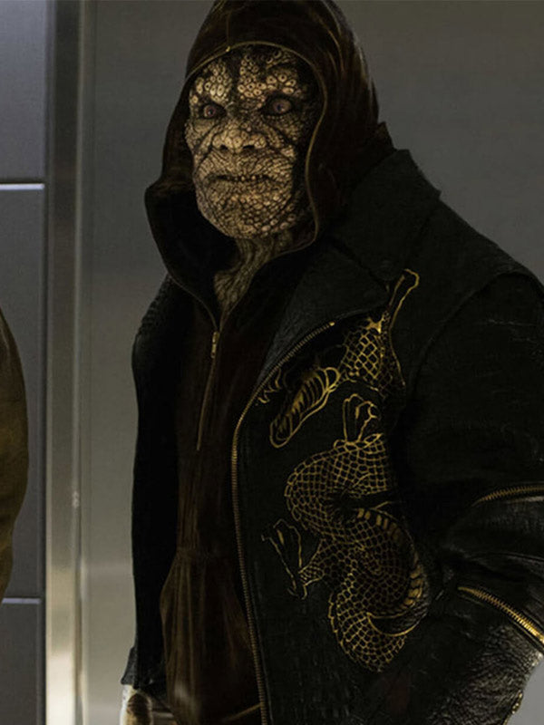 A close-up of a person wearing a black hooded jacket with a gold dragon graphic on the chest, standing indoors against a gray wall.