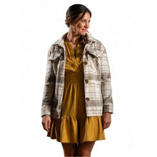 A woman modeling a brown and beige plaid button-up jacket over a mustard yellow dress, photographed against a solid white background.