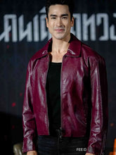 A man wearing a glossy burgundy leather jacket over a black shirt, standing against a dark backdrop with stylized white lettering.