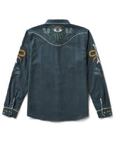 A dark teal western-style shirt jacket shown from the back, featuring white contrast stitching, a central eye motif with wheat, and gold and green sleeve embroidery, set against a plain white background.