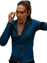 A woman wearing a blue zip-up athletic jacket, shown from the waist up against a plain white background. She has a black armband on her right arm and a black waist bag at the bottom.