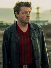 Man wearing a green jacket over a red shirt with a blurred background