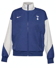 A blue and white Nike track jacket featuring the Tottenham Hotspur crest on the left chest and a white Nike swoosh on the right chest, displayed on a clean white background.