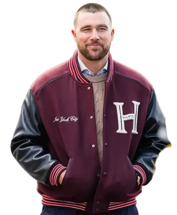 A man wearing a maroon and black varsity jacket with 'New York City' and 'HILTI' embroidery, standing outdoors with a blurred green background.