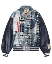 A vintage-style varsity jacket from True Religion, featuring a blue and gray graffiti-patterned front panel with vertical text, dark navy faux-leather sleeves, and striped ribbed collar, cuffs, and hem.